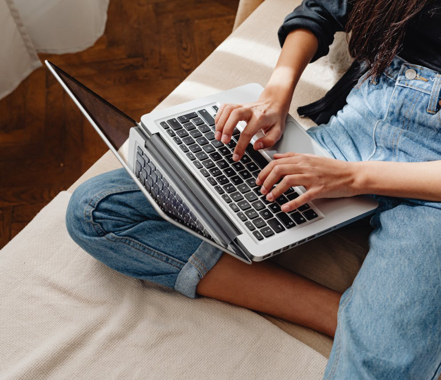 Person using a laptop while sitting on a sofa, representing website creation and online work