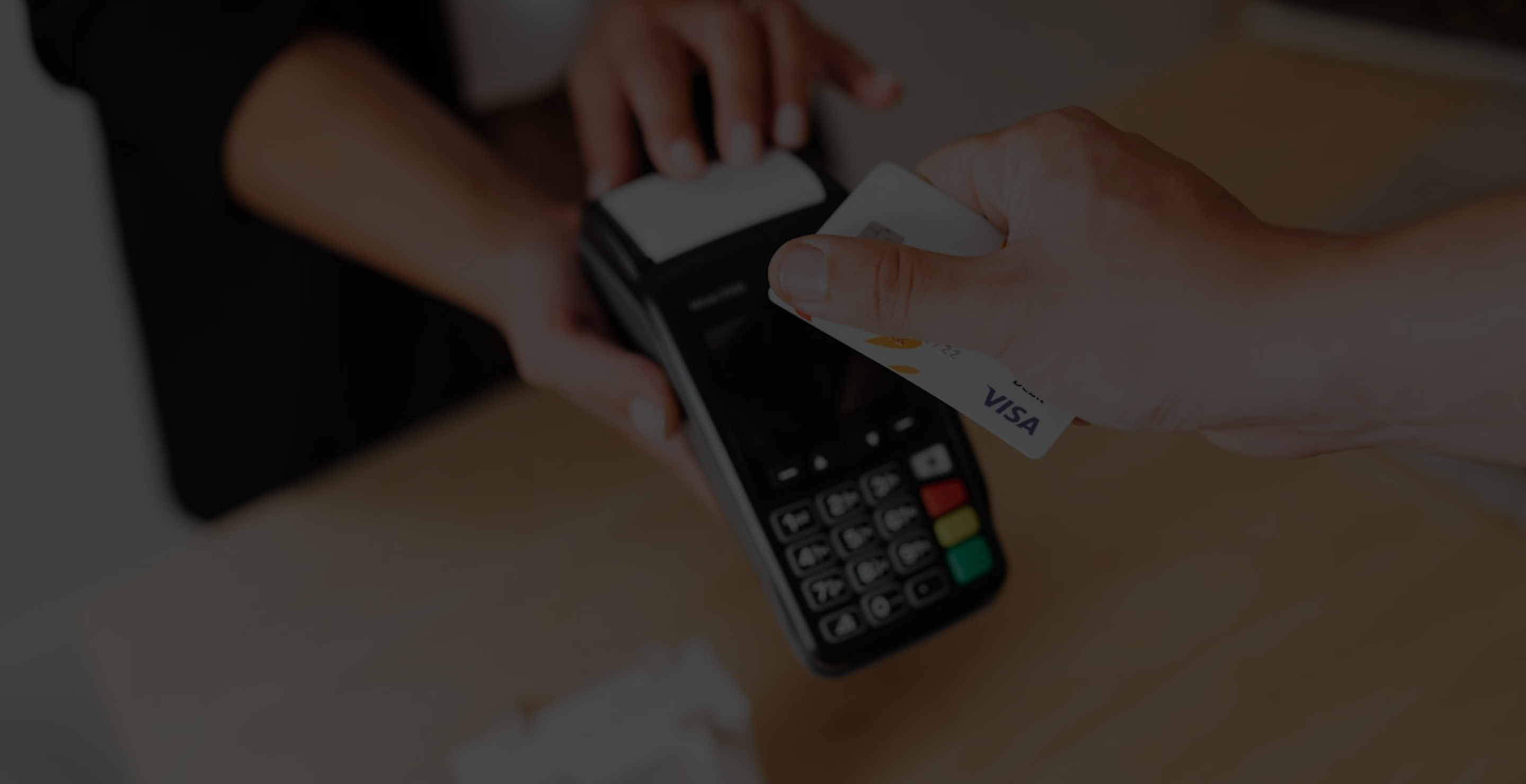 Person tapping a credit card on a POS terminal to complete an in-store payment