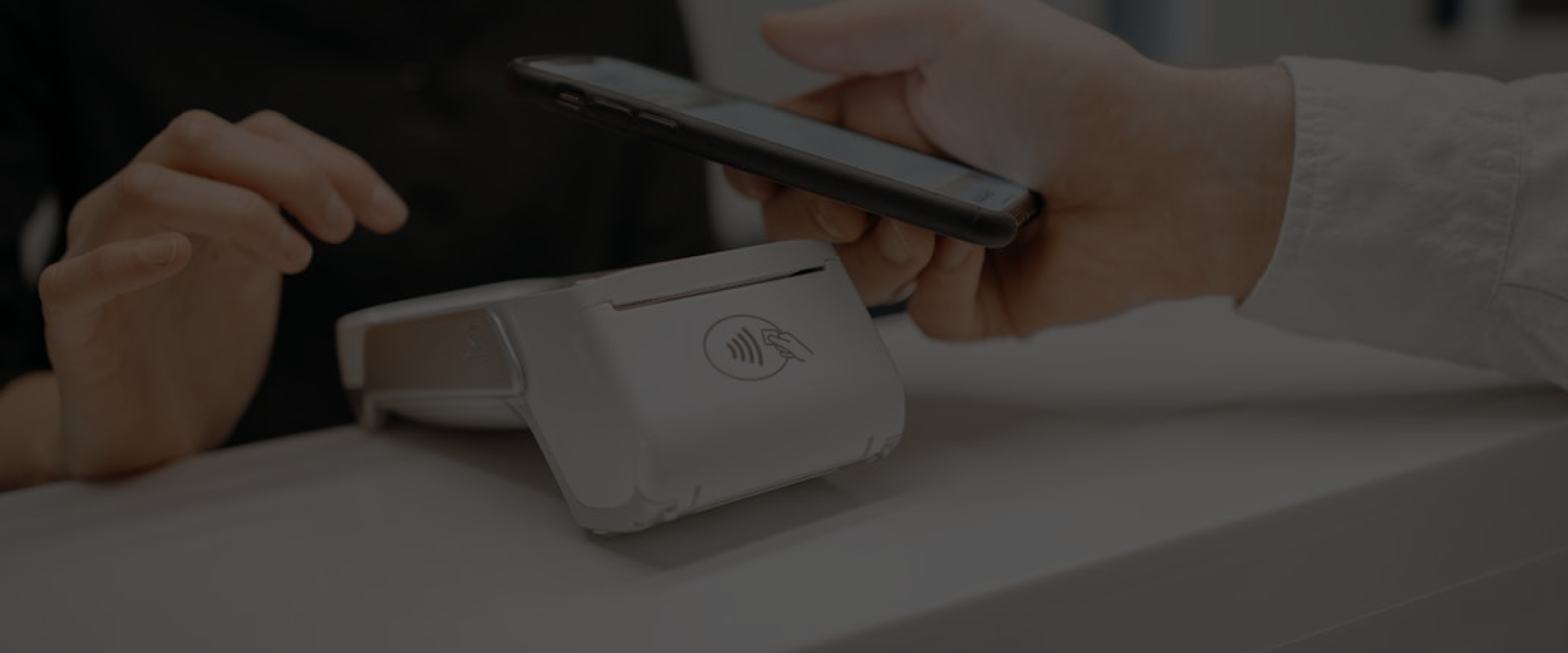 Customer using a smartphone to make a contactless payment on a POS terminal