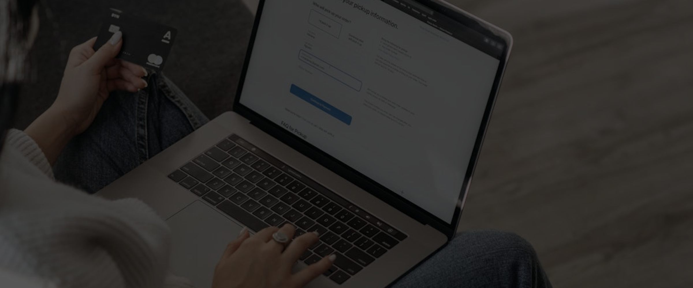 Customer holding a credit card while completing an online checkout on a laptop