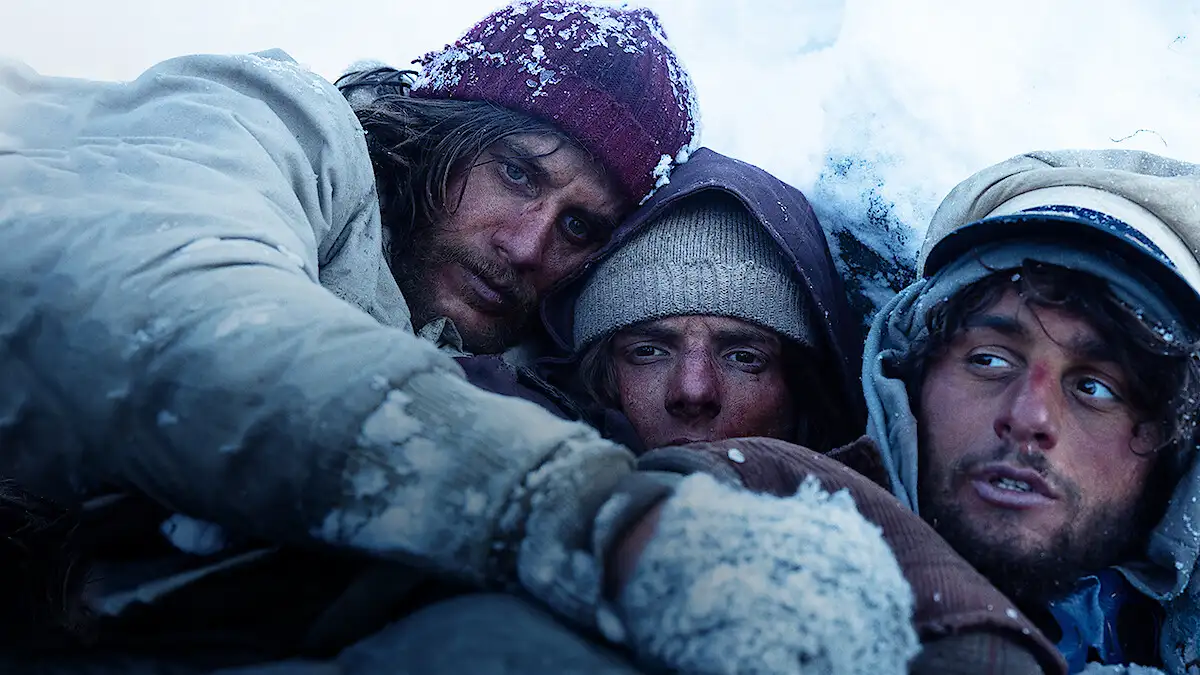 A dramatic scene from the Netflix Original movie 'Society of the Snow,' showing the survivors in the Andes mountains. A dramatic scene from the Netflix Original movie 'Society of the Snow,' showing the survivors in the Andes mountains.