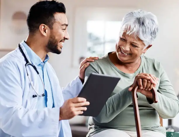 doctor with stethoscope showing tablet to senior woman