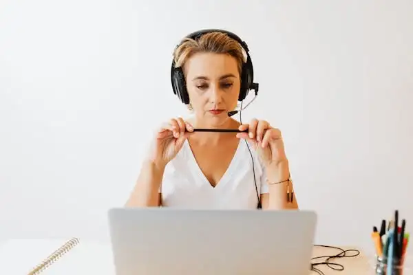 person in headphone holding pen with office supplies