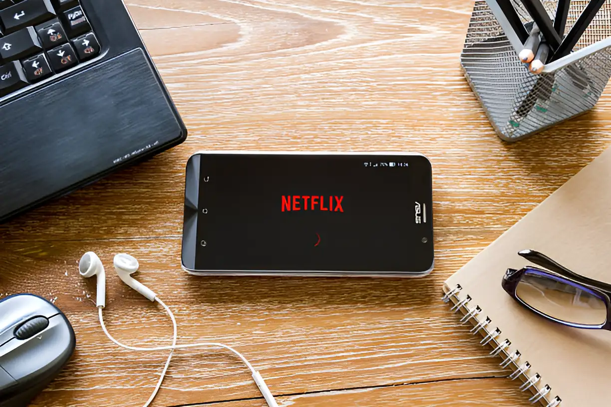 mobile phone logged into netflix with headphones next to it