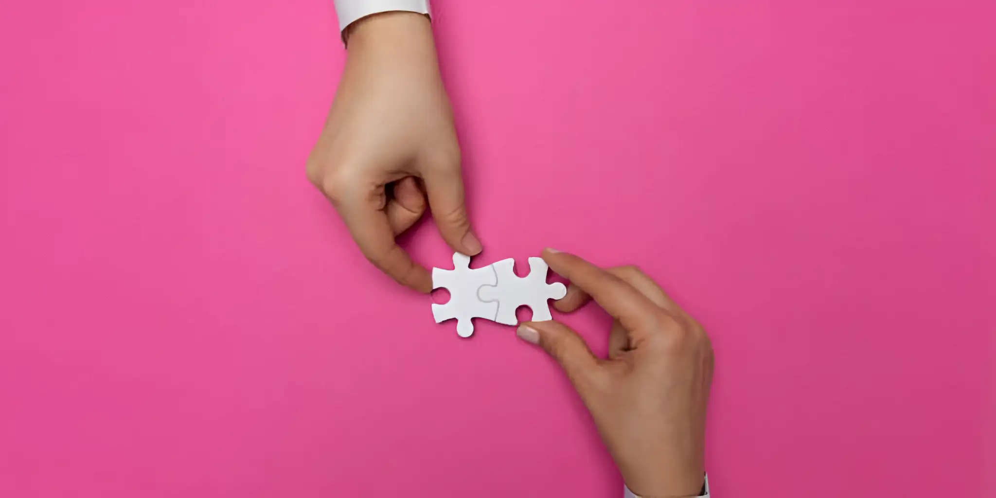 two hands putting together white puzzle pieces
