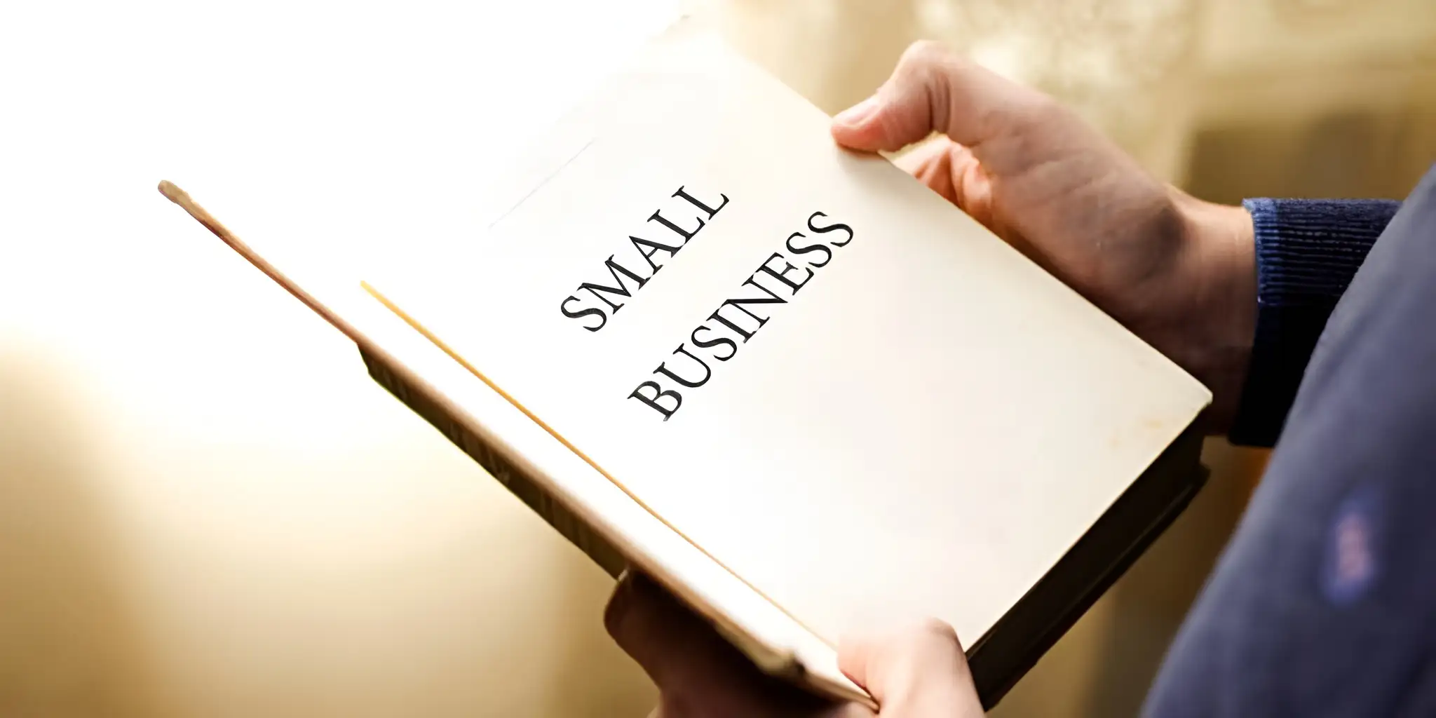 a person opening the pages of a book about small business