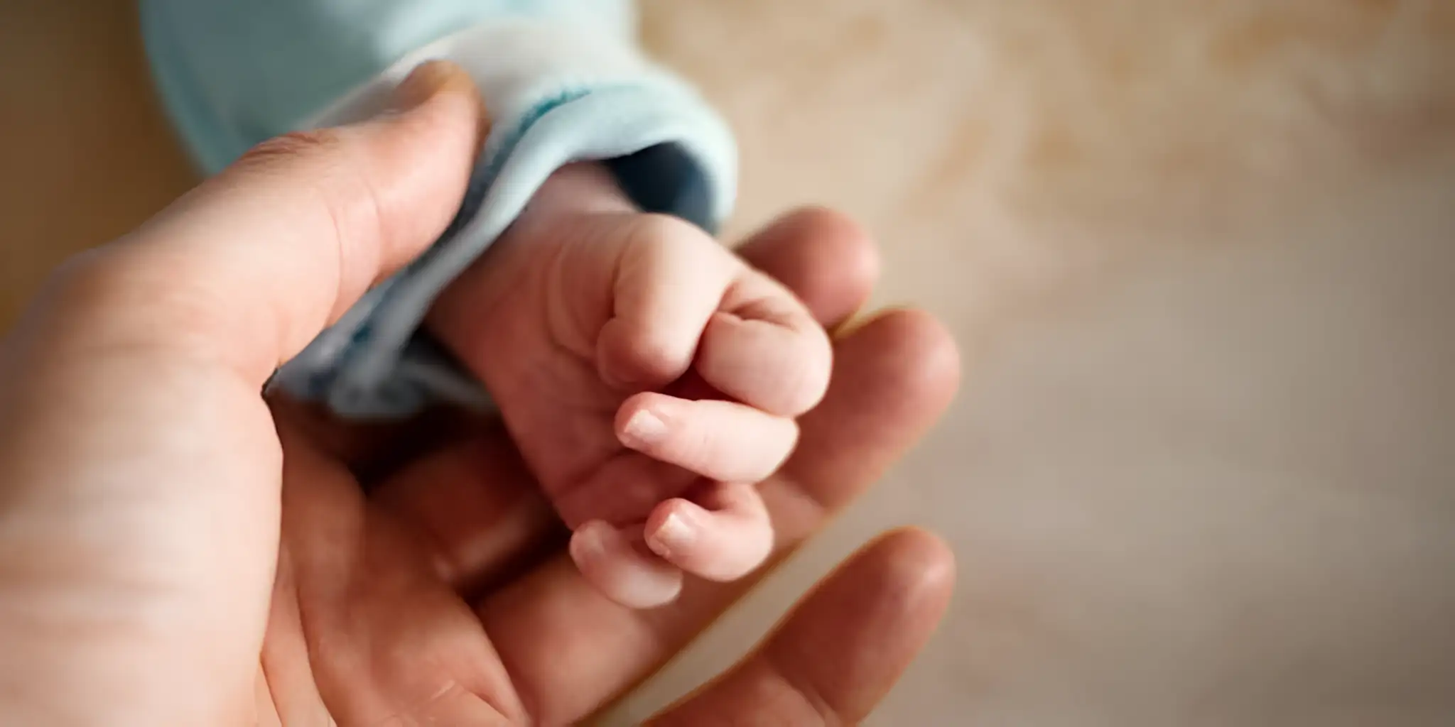 a father's hand holding a baby's hand