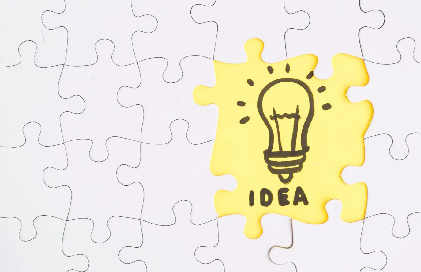 Yellow idea jigsaw puzzle stands out from the white pieces
